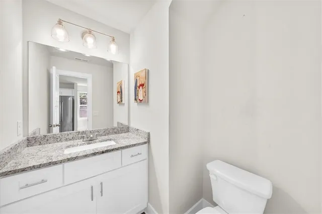 a bathroom with a granite countertop sink mirror vanity and toilet