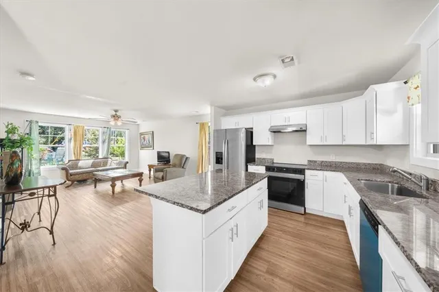 a kitchen with granite countertop center island wooden floor and stainless steel appliances