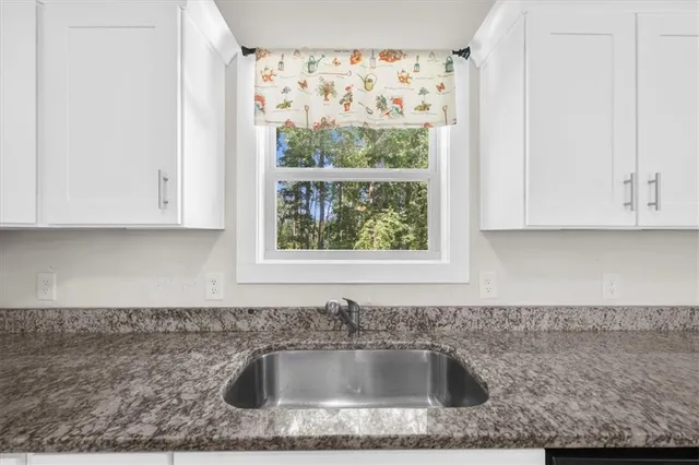 a kitchen with granite countertop white cabinets and sink