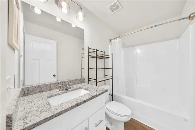 a bathroom with a granite countertop sink a toilet and shower