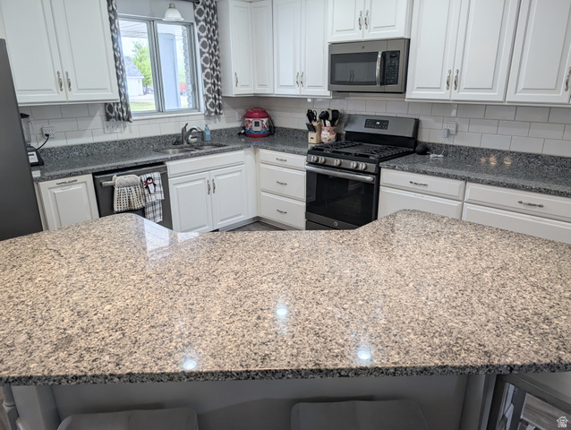 897 East 1200 North Mapleton, UT 84664 - Photo 10 of 54 Kitchen with stainless steel appliances, white cabinetry, dark stone counters, and decorative backsplash