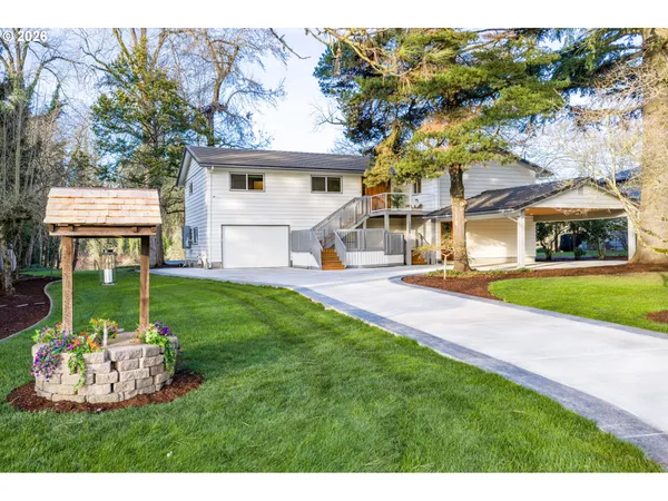 a view of a house with a big yard and large trees