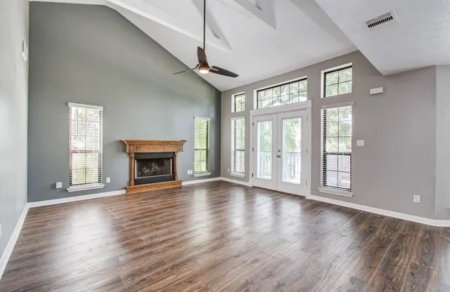 an empty room with wooden floor fireplace and windows