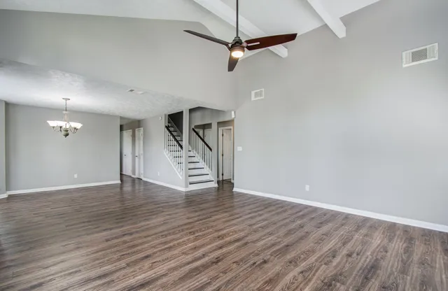 a view of an empty room with wooden floor a ceiling fan