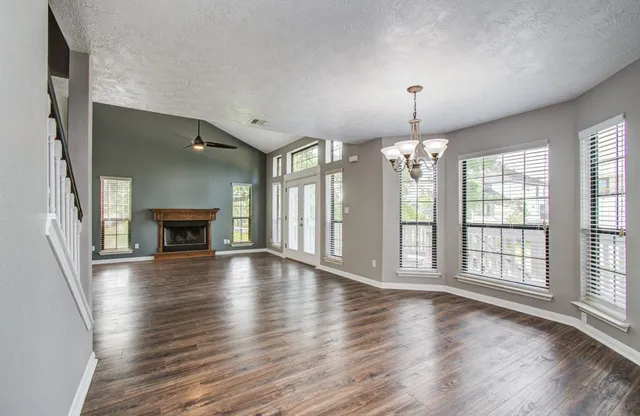 an empty room with wooden floor fireplace and windows