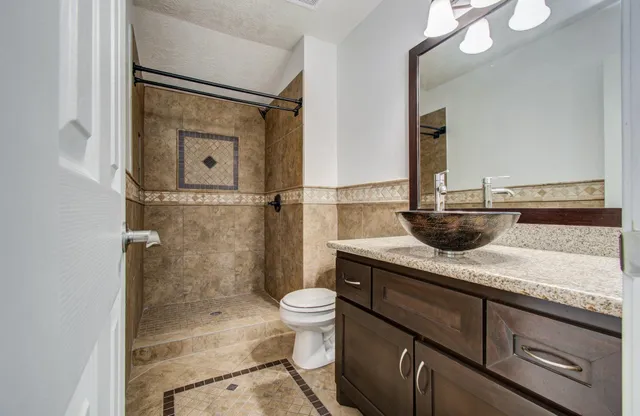 a bathroom with a granite countertop sink a toilet and shower