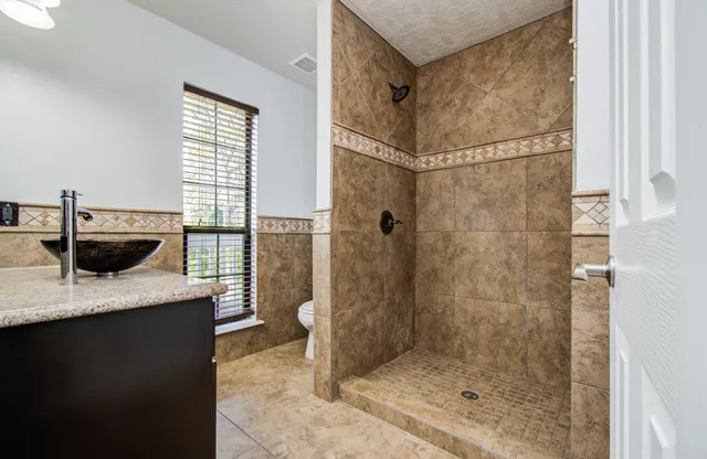 a bathroom with a granite countertop sink a toilet and shower