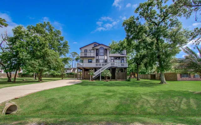 a view of a house with a big yard and large trees