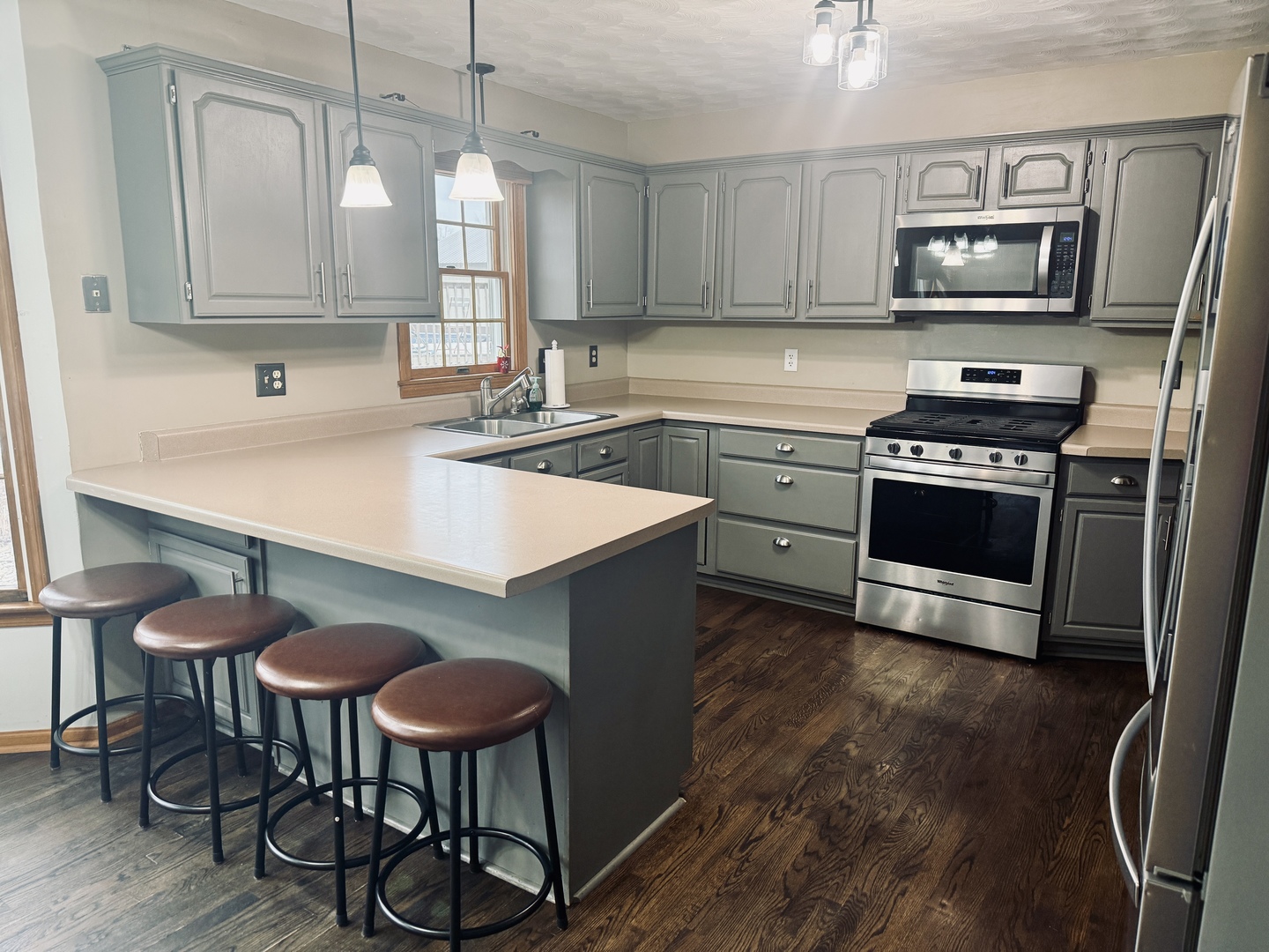 10151 East Hickory Ridge Drive Rochelle, IL 61068 - Photo 8 of 31 a kitchen with stainless steel appliances a stove a sink a microwave a dining table and chairs with wooden floor