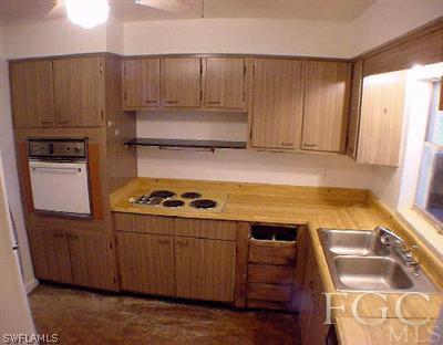 107 Texas Road, Unit 20 Lehigh Acres, FL 33936 - Photo 4 of 6 a kitchen with wooden cabinets and a stove top oven