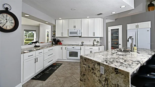 a kitchen with granite countertop white cabinets and white appliances