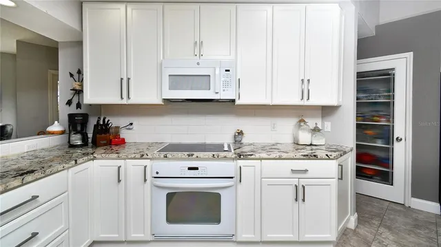 a kitchen with stainless steel appliances granite countertop a stove a sink and white cabinets