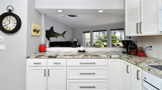 a kitchen with kitchen island granite countertop a stove a sink and a white cabinets