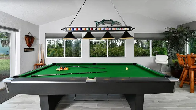 a room with pool table windows and wooden floor