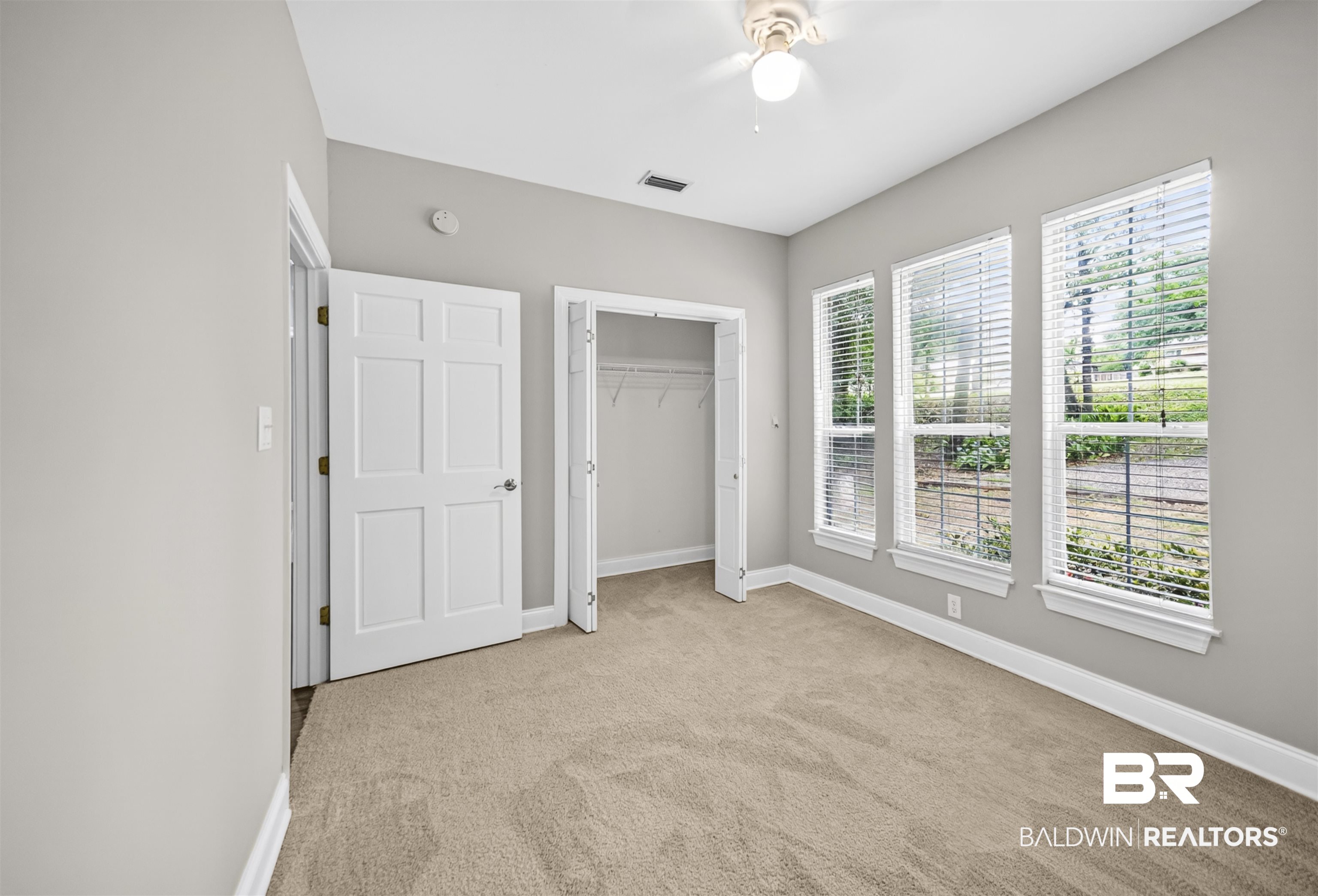 5913 Antoine Road Mobile, AL 36693 - Photo 17 of 33 Room with three tall windows, light neutral wall paint, and beige carpet flooring