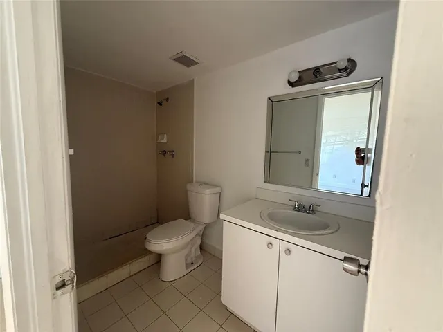 a bathroom with a granite countertop toilet sink and mirror