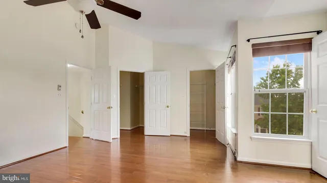 a view of empty room with wooden floor and fan
