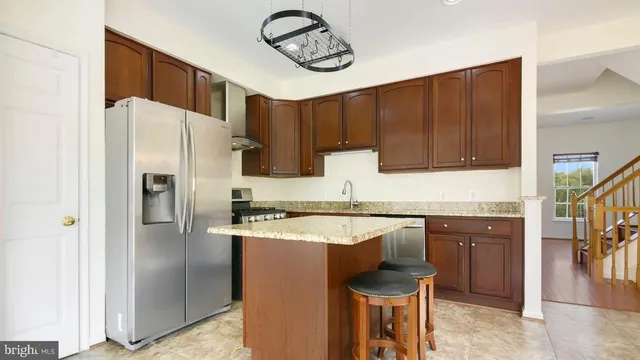 a kitchen with granite countertop a refrigerator stove top oven and sink