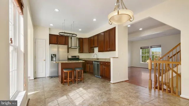 a kitchen with kitchen island granite countertop a refrigerator and a sink
