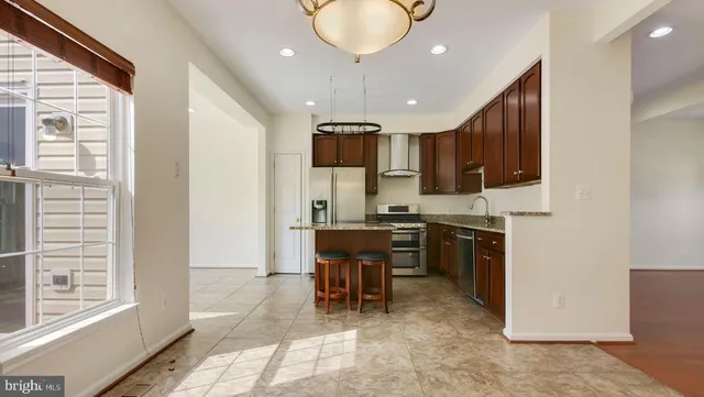 a kitchen with kitchen island granite countertop a counter space a sink appliances and cabinets