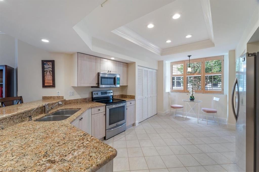 6549 Marissa Loop, Unit 15 Naples, FL 34108 - Photo 5 of 24 a large kitchen with kitchen island granite countertop a sink and a stove top oven