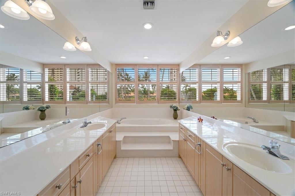 6549 Marissa Loop, Unit 15 Naples, FL 34108 - Photo 9 of 24 a bathroom with a tub a sink a large mirror and a shower