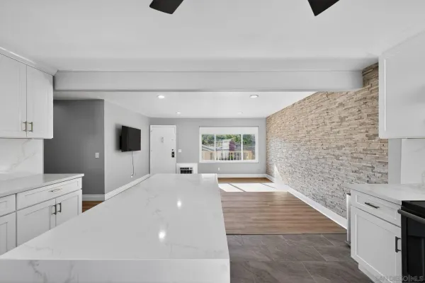 a large white kitchen with granite countertop a stove a sink and a microwave
