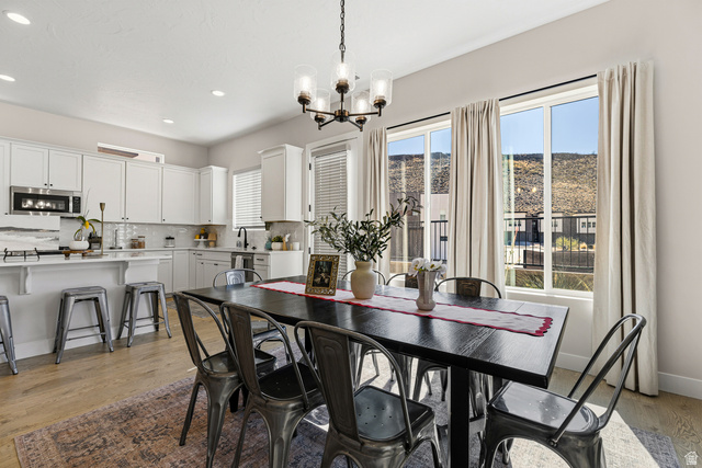 839 Walker Way St. George, UT 84770 - Photo 5 of 32 Bright dining area featuring a linear chandelier over a dark wood-finish table, wood-finish flooring, and expansive windows