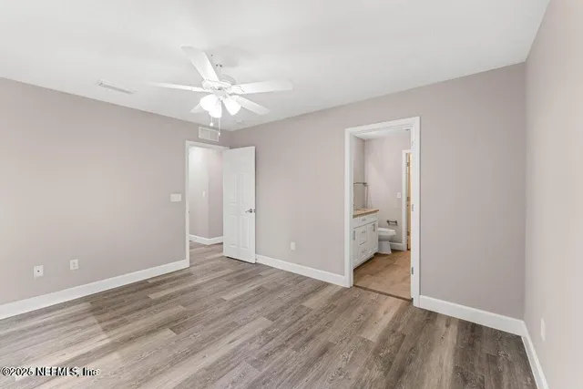 an empty room with wooden floor and ceiling fan