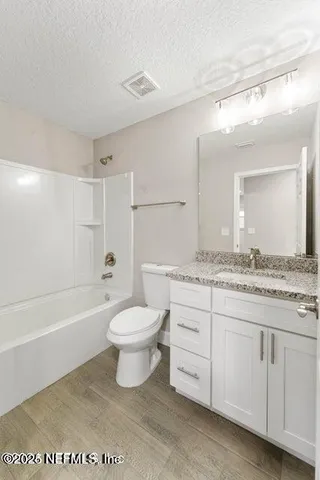 a bathroom with a granite countertop toilet a sink and a bathtub