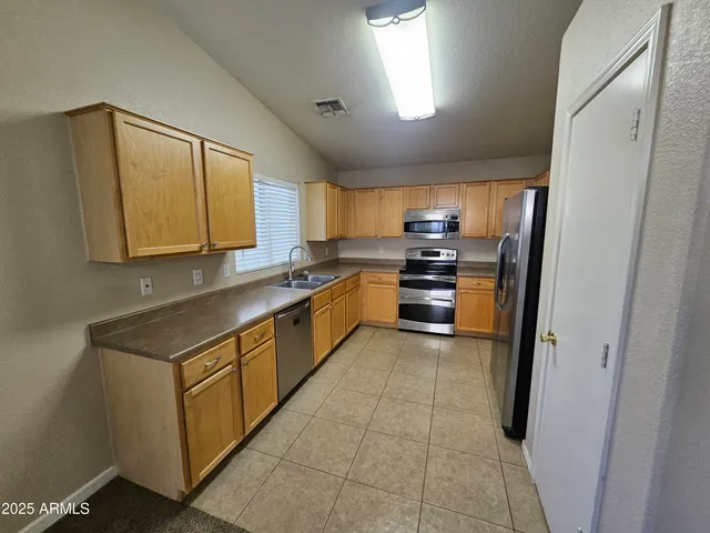 a kitchen with stainless steel appliances granite countertop a stove a sink and a refrigerator
