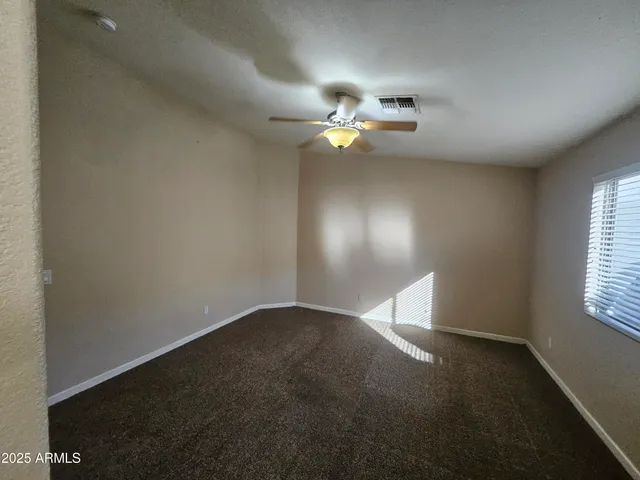 an empty room with windows and fan