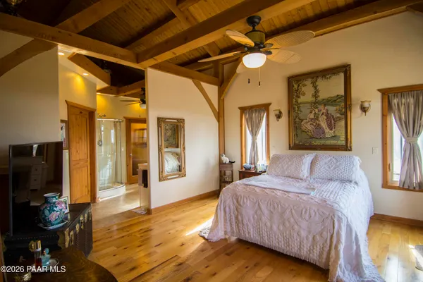 a bedroom with a bed a flat tv screen and dresser next to a window