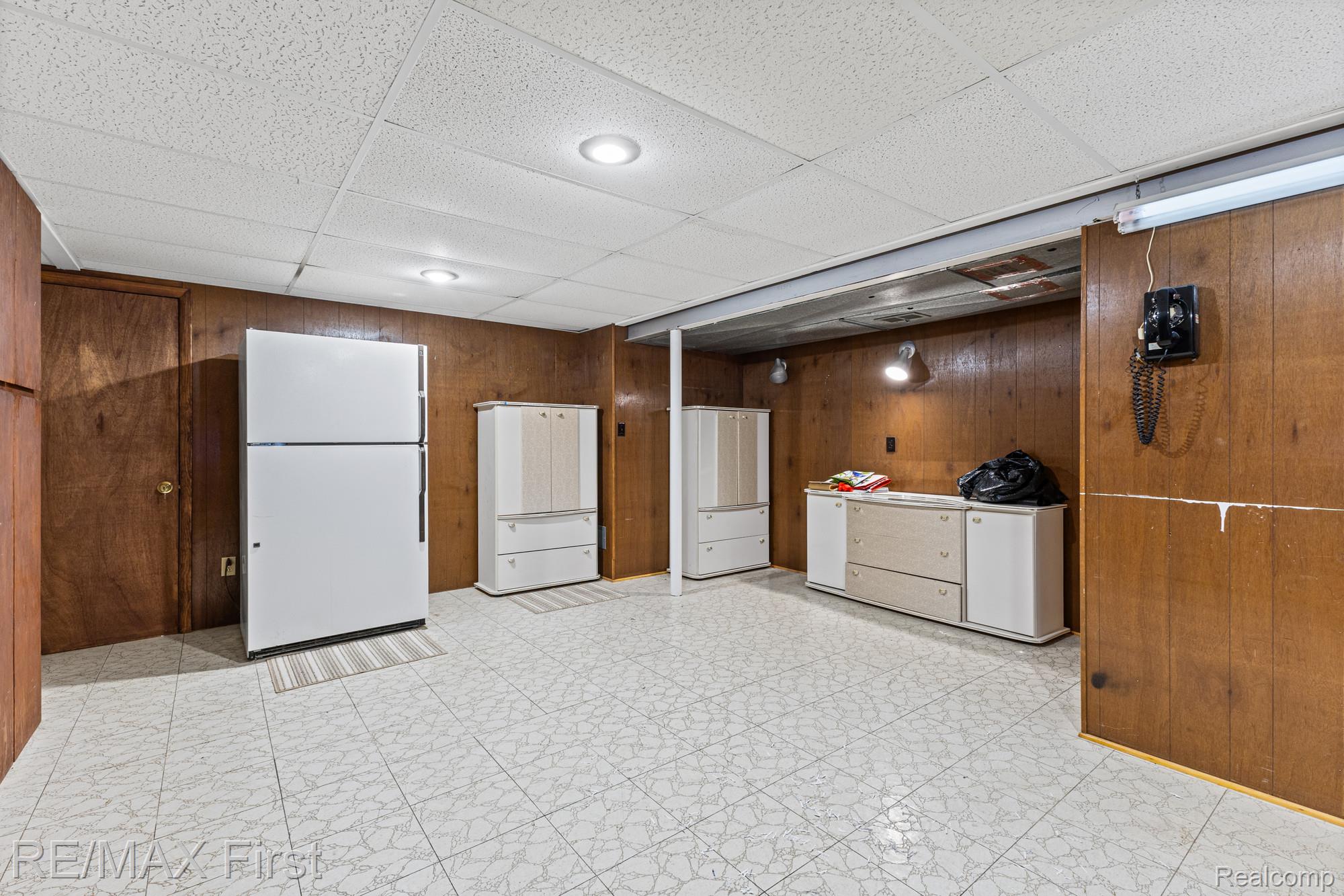 34356 Greentrees Road Sterling Heights, MI 48312 - Photo 32 of 40 Kitchen featuring a paneled ceiling, freestanding refrigerator, light flooring, and wood walls