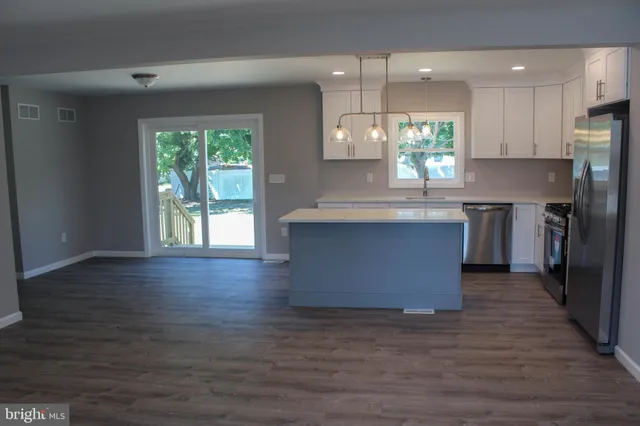 an open kitchen with wooden floor and stainless steel appliances