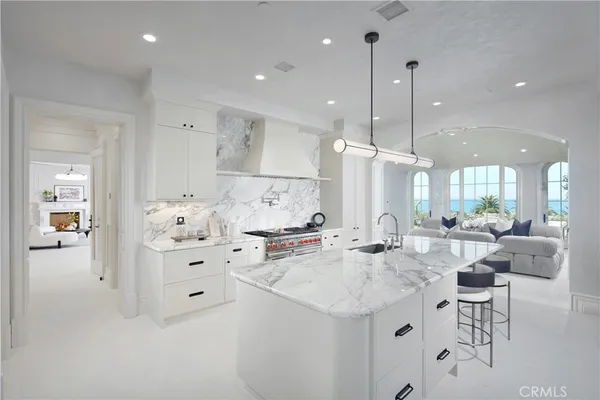 a large white kitchen with cabinets a sink a window and stainless steel appliances