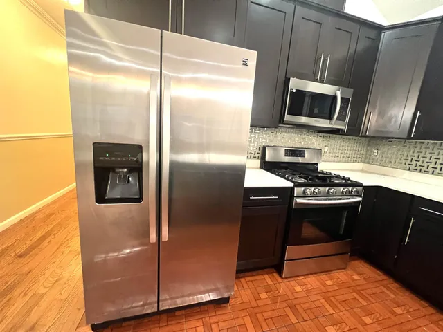 a kitchen with stainless steel appliances granite countertop a refrigerator a stove and a sink with wooden floor