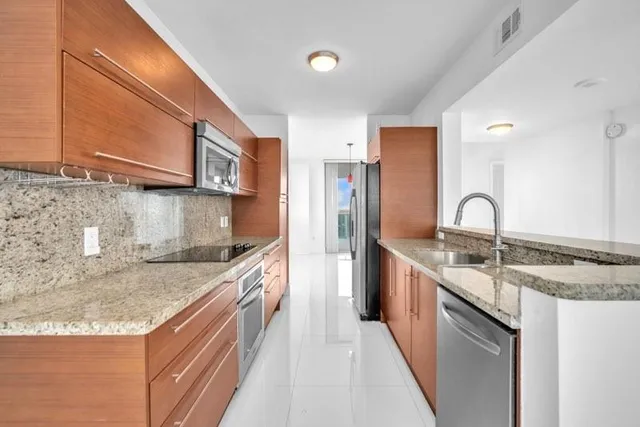 a kitchen with stainless steel appliances granite countertop a sink and dishwasher a stove top oven with wooden floor