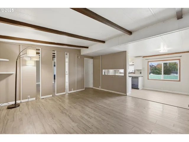 a view of an empty room with window and wooden floor