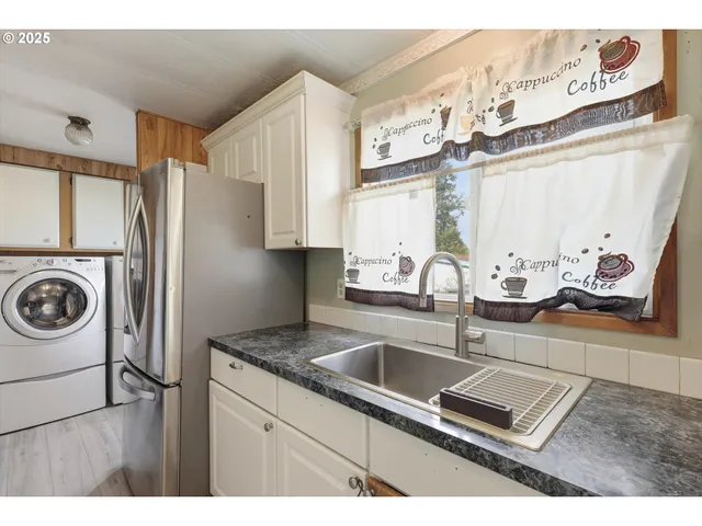 a kitchen with stainless steel appliances granite countertop a sink a stove a refrigerator and cabinets