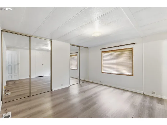 a view of an empty room with wooden floor & closet