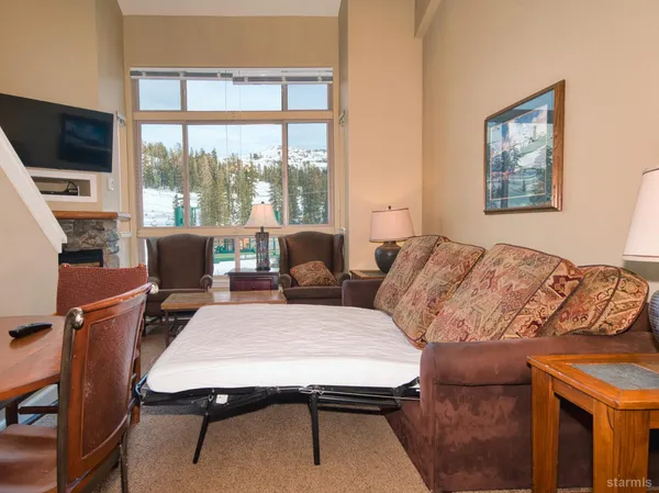 a living room with furniture a flat screen tv and a floor to ceiling window