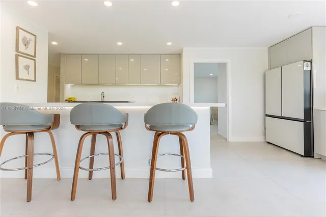 a kitchen with stainless steel appliances a dining table chairs and a refrigerator