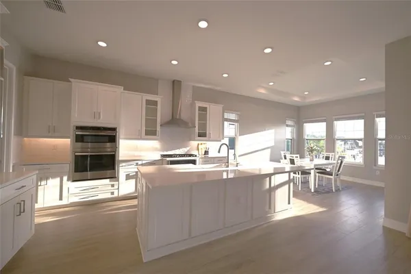 a large kitchen with lots of counter space a sink appliances and chairs