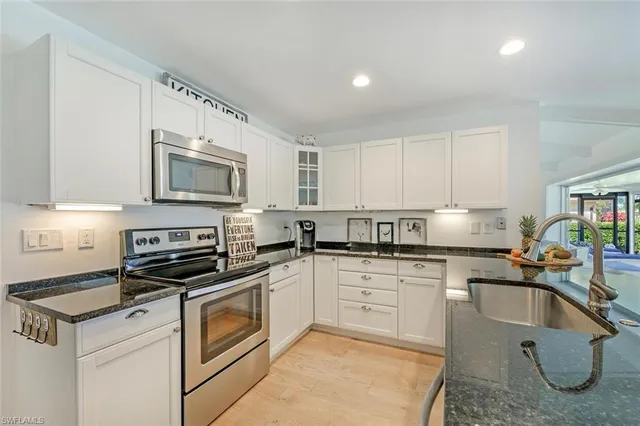 a kitchen with granite countertop a sink a stove top oven and cabinets