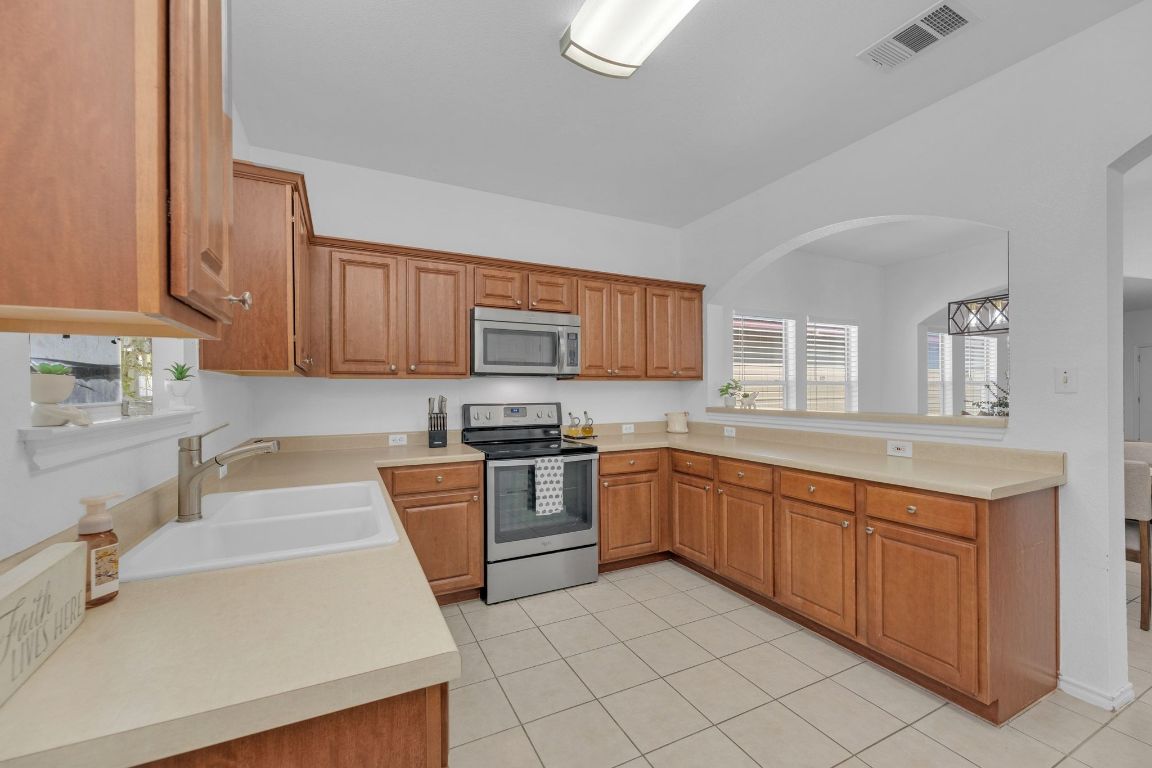 8901 Meridian Oak Lane Austin, TX 78744 - Photo 10 of 26 a kitchen with stainless steel appliances granite countertop a sink and dishwasher a stove top oven with white cabinets