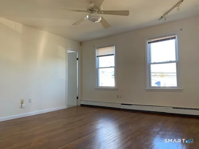 an empty room with wooden floor and windows