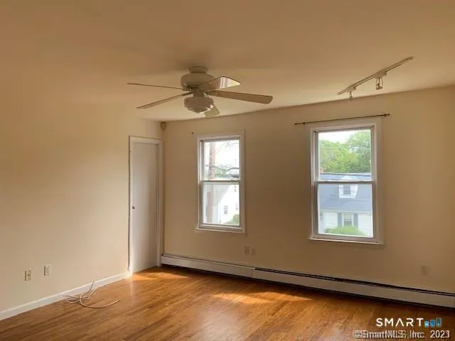 a view of an empty room with a window and wooden floor