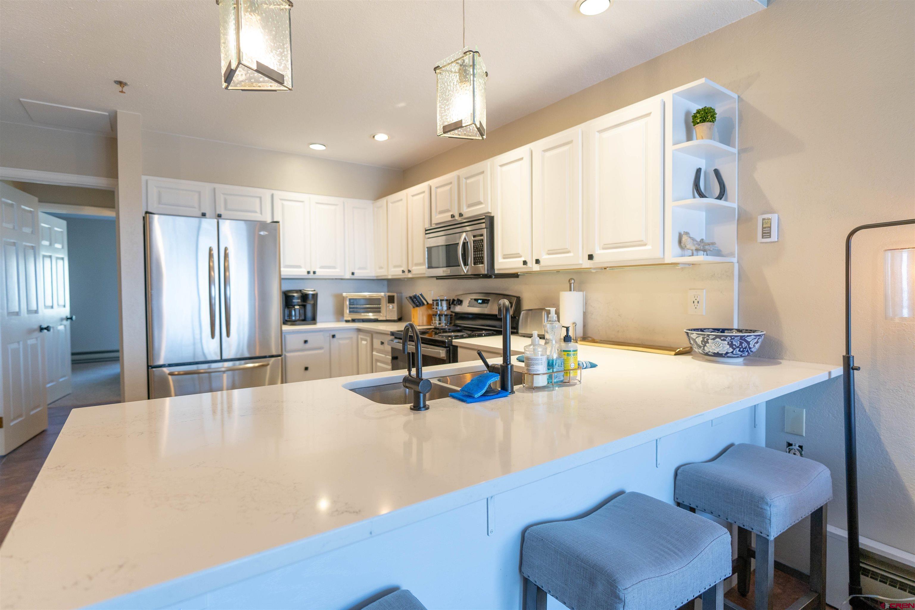12 Snowmass Road, Unit 414 Crested Butte, CO 81225 - Photo 15 of 33 a kitchen with stainless steel appliances granite countertop a sink a stove a refrigerator cabinets and chairs