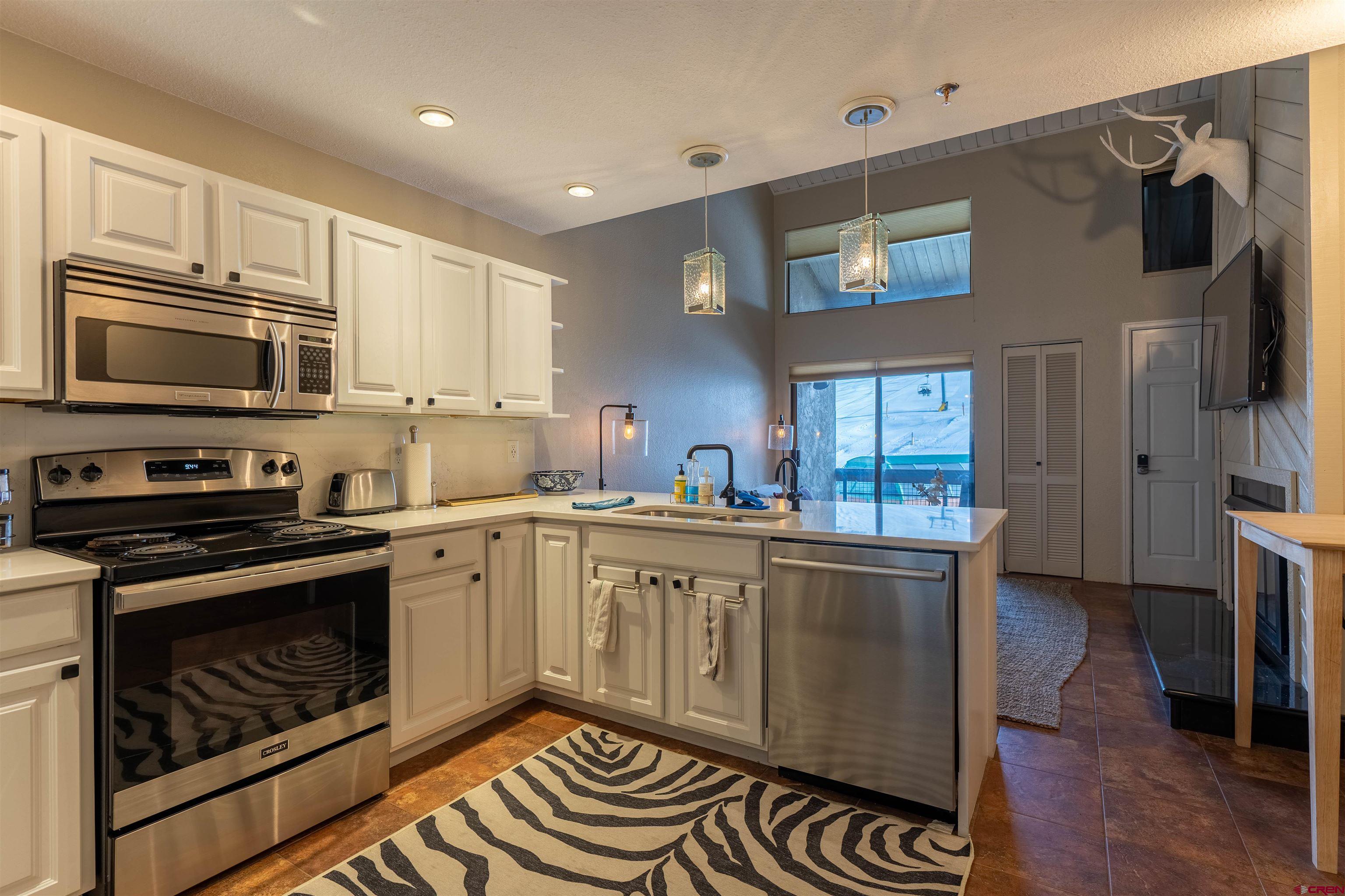 12 Snowmass Road, Unit 414 Crested Butte, CO 81225 - Photo 19 of 33 a kitchen with stainless steel appliances a stove a sink and a microwave